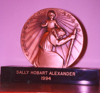 The front of the Christopher Medal shows St. Christopher, ready to cross the water, carrying the little boy who grows heavier and heavier because he turns out to be Jesus. At the base, my name and the year 1994 are engraved.